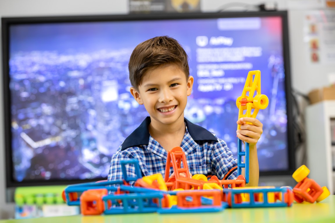 Image of student smiling and building with blocks in the classroom